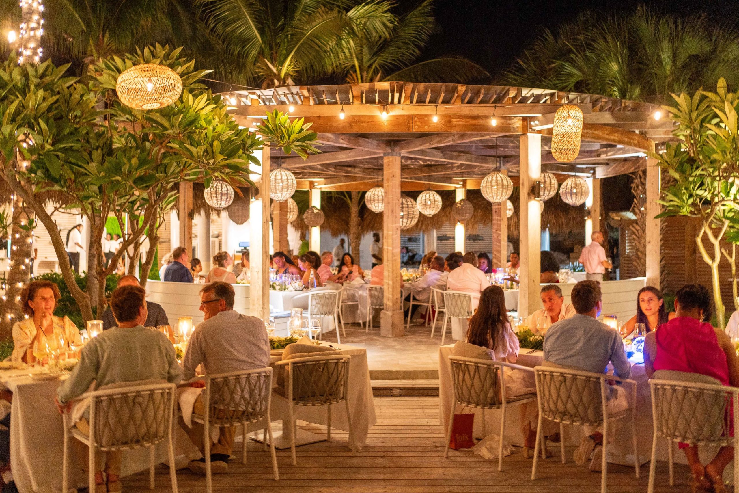 Elegant outdoor dining at Infiniti Restaurant, adorned with string lights and surrounded by lush greenery in Turks and Caicos.