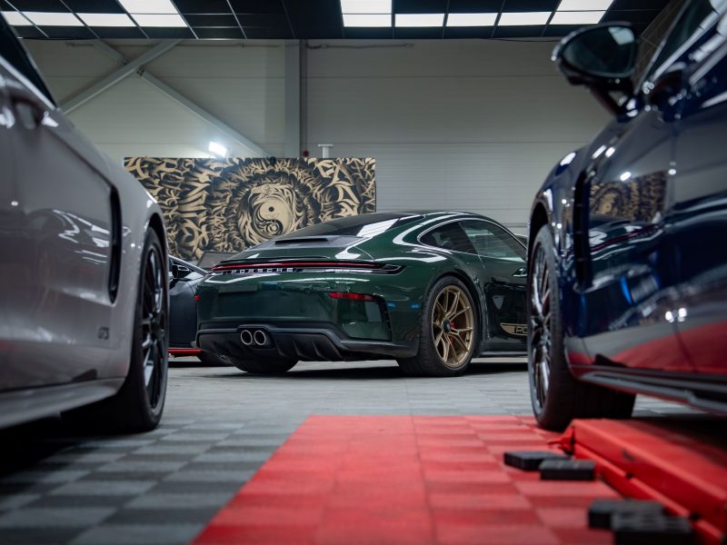 Luxury garage condos showcasing a green Porsche surrounded by other high-end vehicles in a stylish interior.