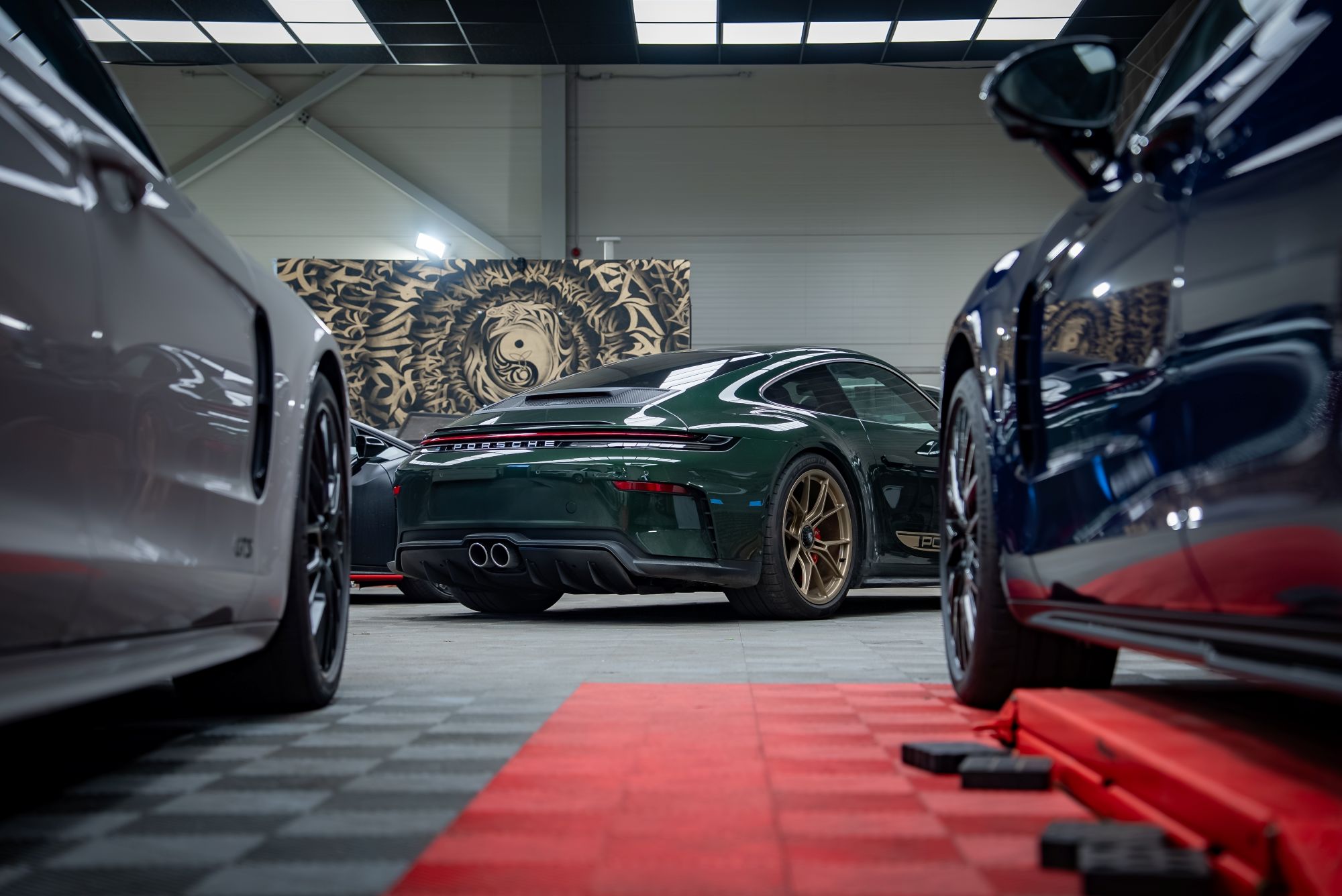 Luxury garage condos showcasing a green Porsche surrounded by other high-end vehicles in a stylish interior.