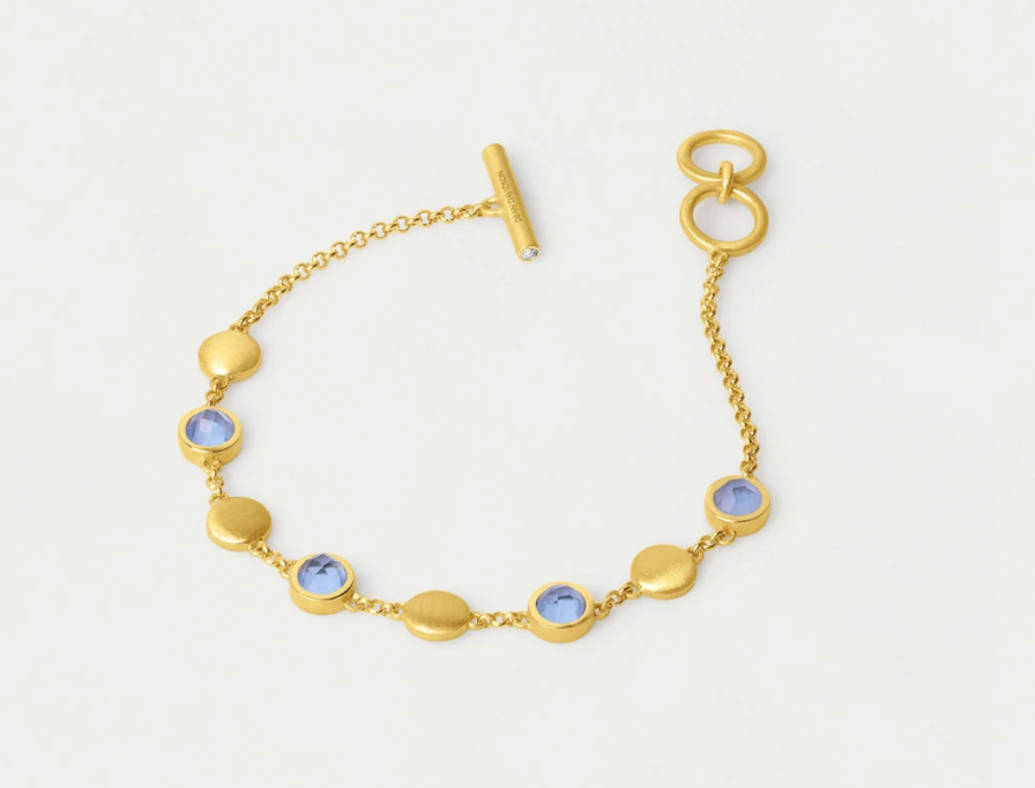 Gold bracelet featuring blue gemstones and textured circular elements, perfect for an elevated look this Labor Day weekend.