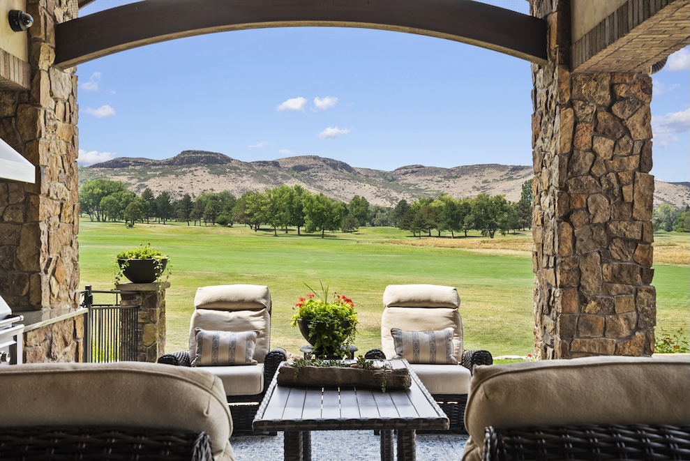 View from a patio overlooking a golf course, with mountains and trees in the background, creating a serene outdoor space.