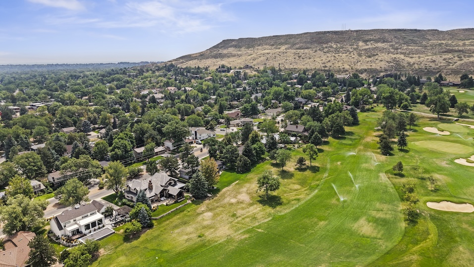 Aerial view of a golf course surrounded by residential neighborhoods and rolling hills in Golden, Colorado.