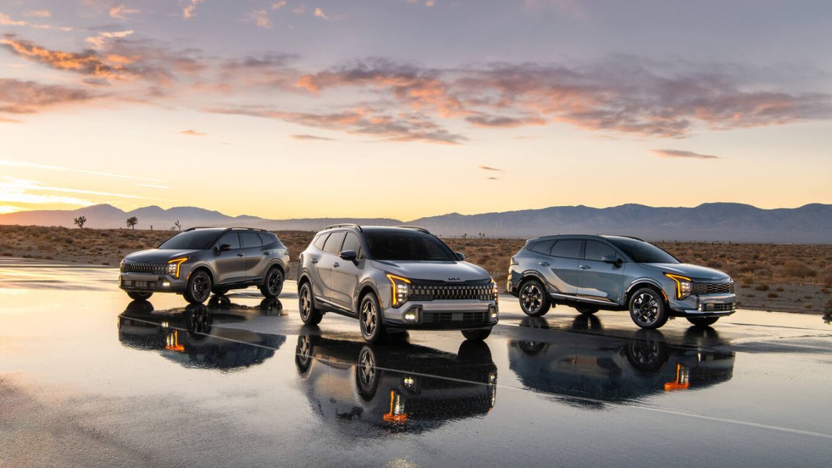 Three Kia SUVs are parked on a reflective surface at sunset, showcasing their sleek designs against a desert backdrop.