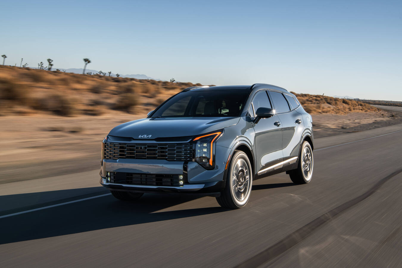 Kia 2027 Sportage X-Line Prestige Plug-In Hybrid SUV driving on a smooth road with a desert backdrop.
