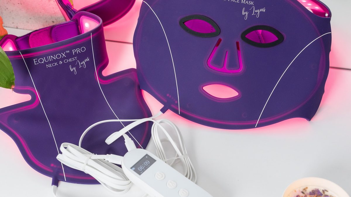LED face mask and neck treatment by Equinox, featuring purple design with glowing lights, control remote, and relaxing ambiance.