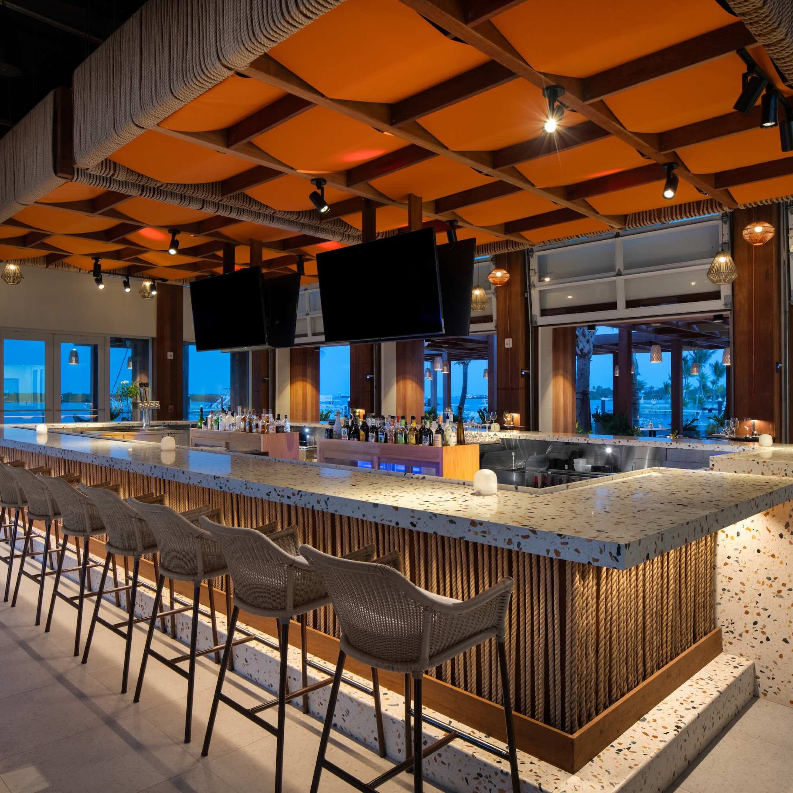 Stylish bar area at Anchorage Restaurant with sleek countertops, high stools, and large windows showcasing the dockside view.