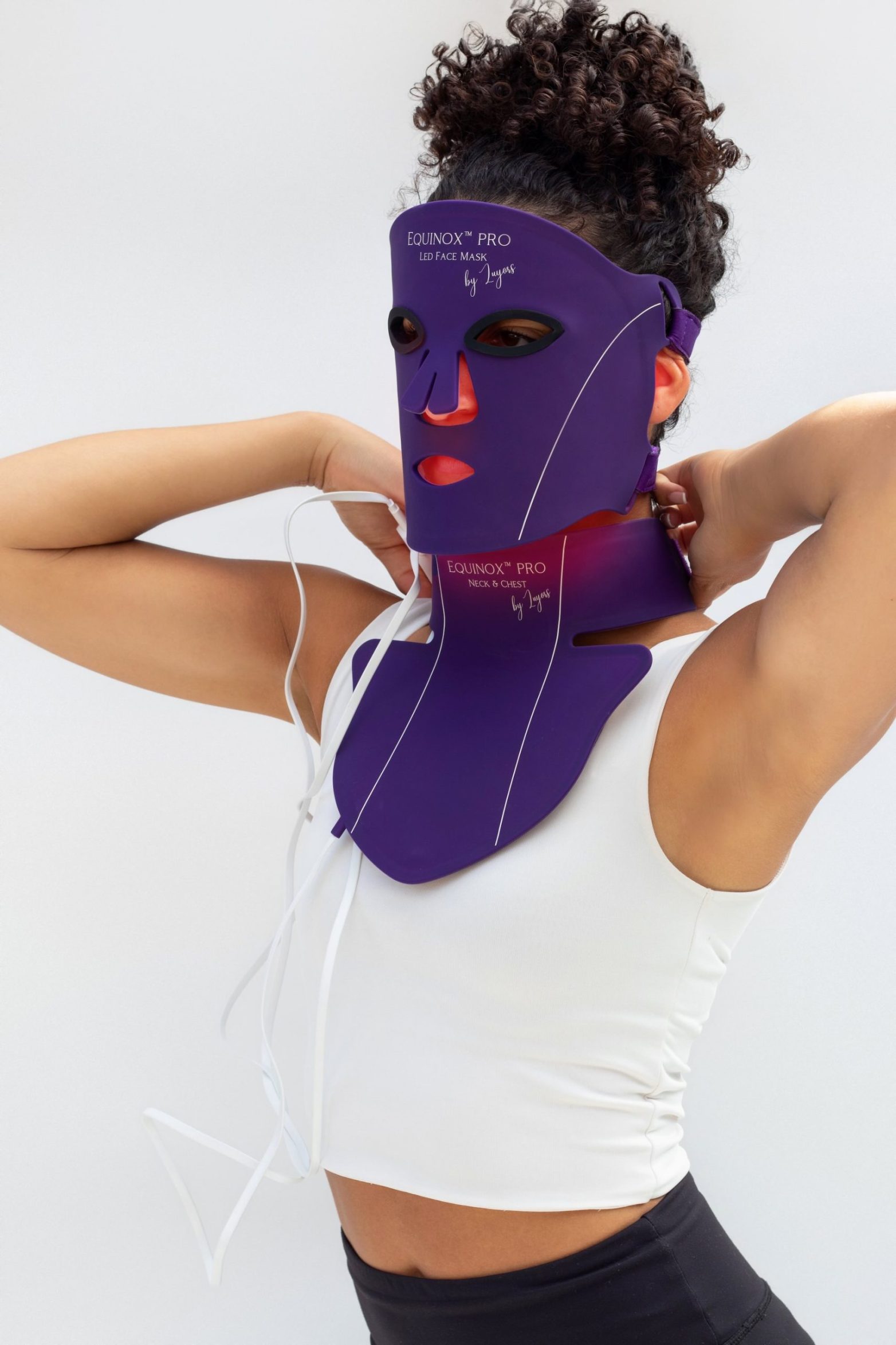 Woman wearing a purple LED face mask for light therapy, demonstrating at-home skincare.