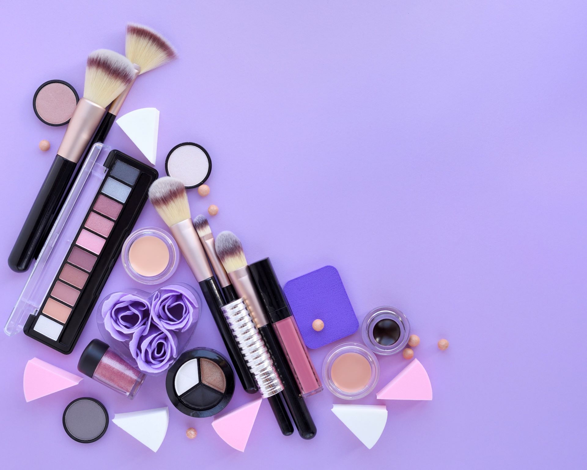 Cosmetic brushes and makeup products arranged on a lavender background, highlighting beauty course offerings in WA.