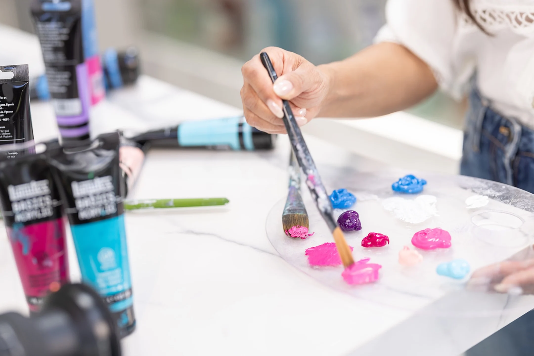 A hand selecting vibrant paint colors from a palette while preparing to create art at a studio workspace.