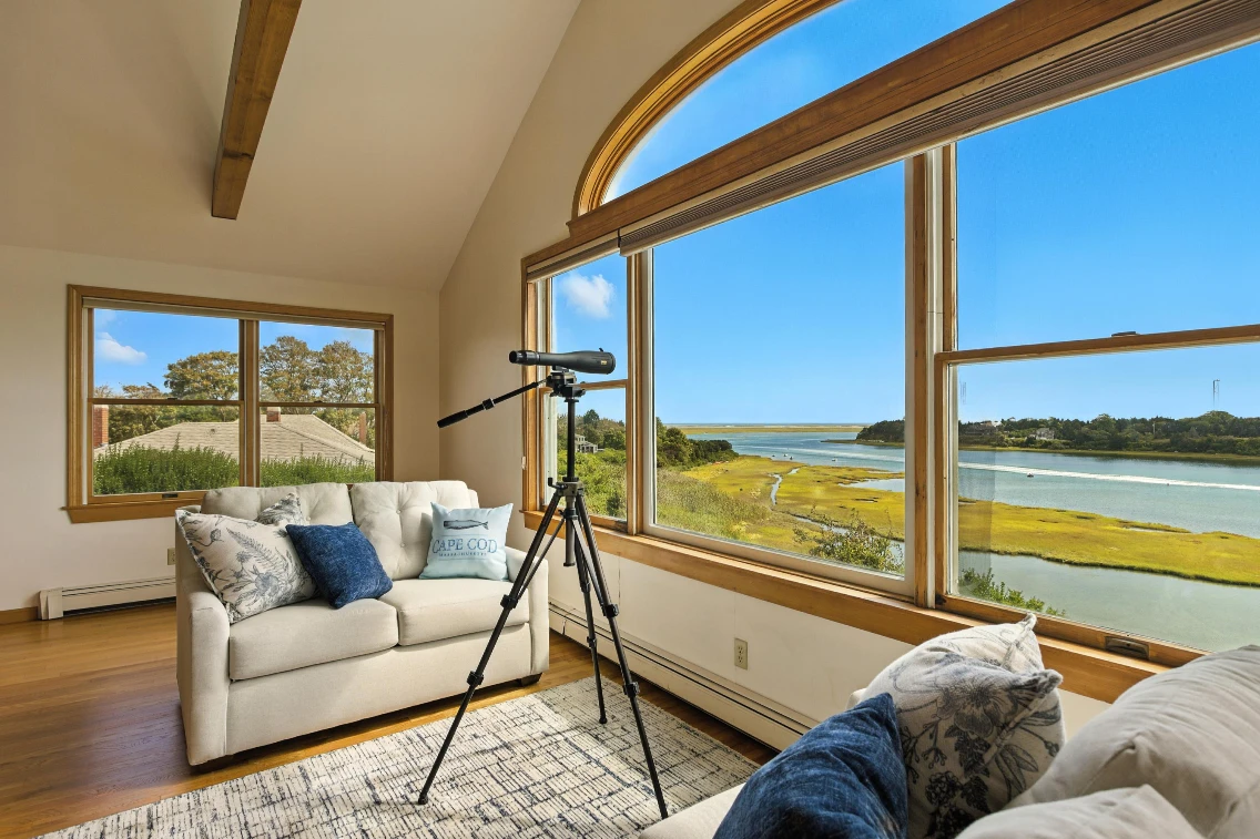 Cozy living space featuring a telescope, comfortable seating, and expansive water views in a Cape Cod retreat.