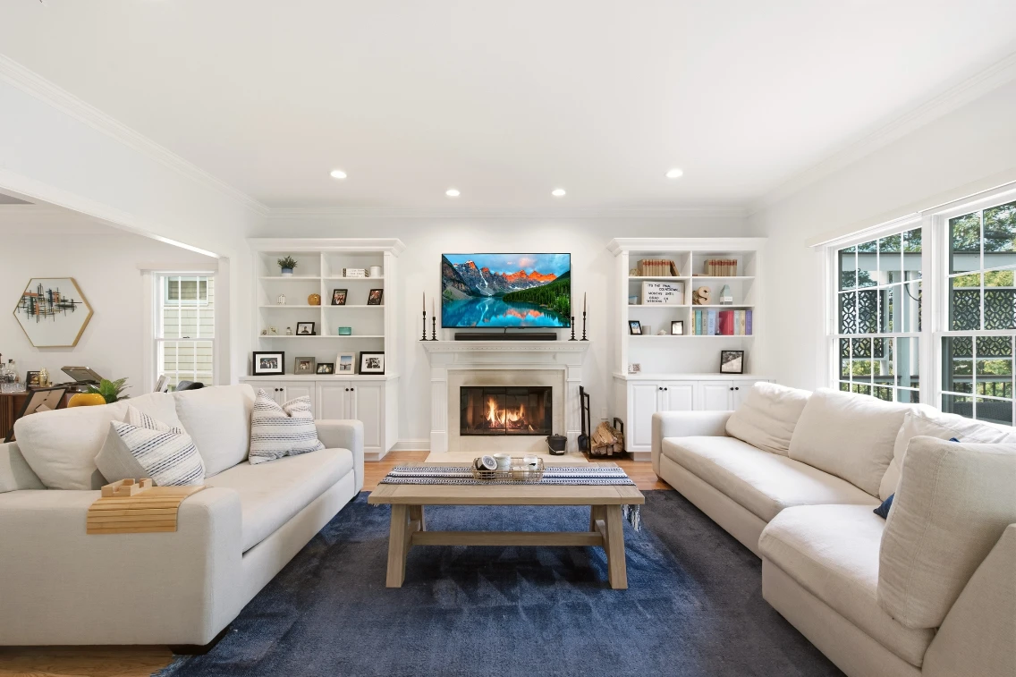 Modern living room featuring two sofas, a coffee table, a fireplace, and a TV displaying scenic mountain views.