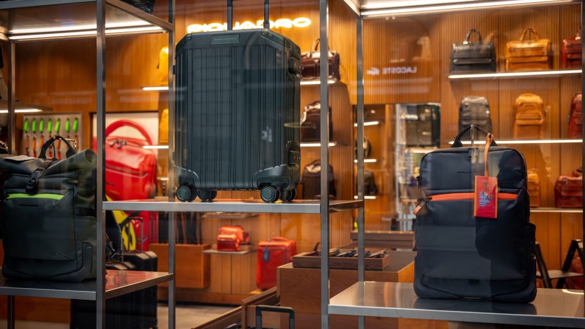 Designer luggage showcased in a store display, featuring a hard-shell suitcase and a backpack against a stylish background.