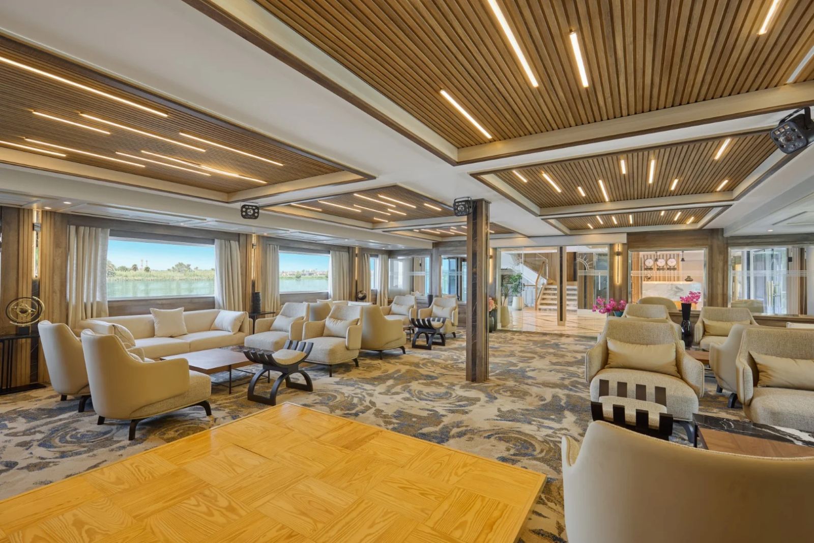 Spacious lounge area featuring modern seating, elegant decor, and large windows overlooking the Nile River.