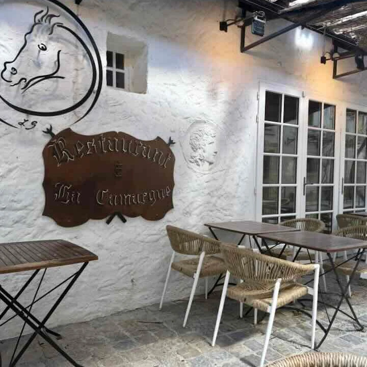 Charming outdoor dining area at Restaurant La Camargue in Aigues-Mortes, featuring rustic tables and a decorative wall.