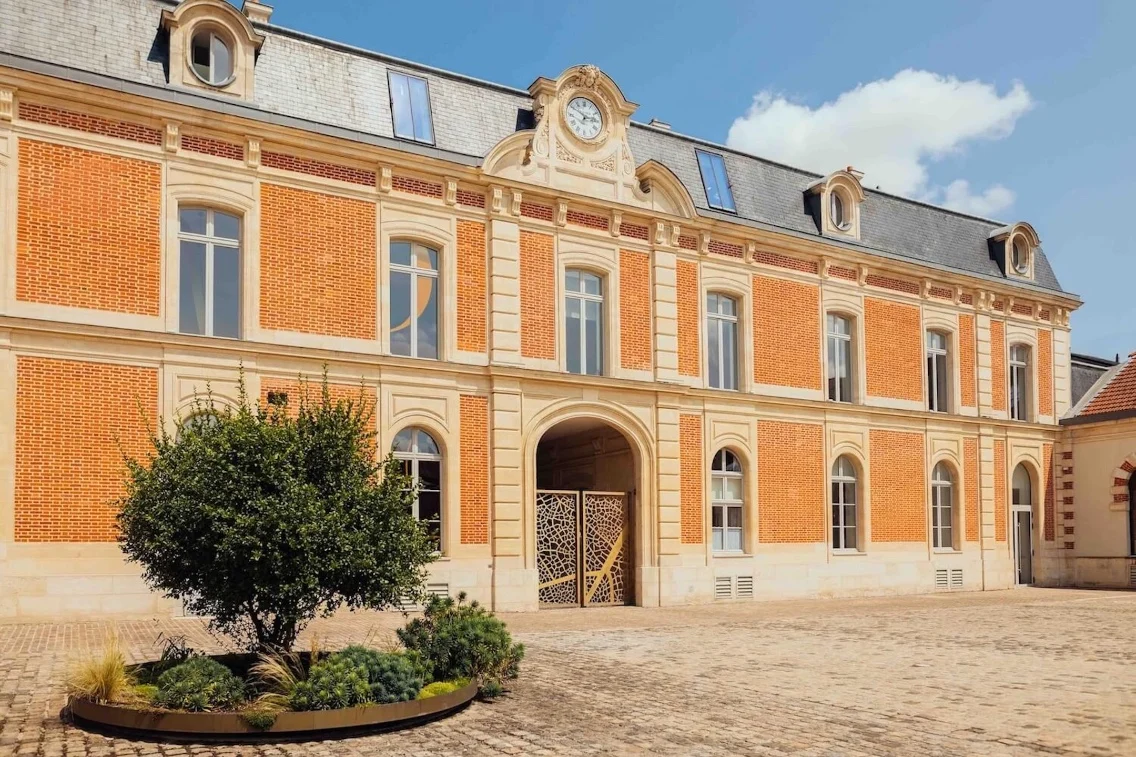 The Louis Roederer headquarters featuring elegant red brick architecture and a landscaped courtyard.