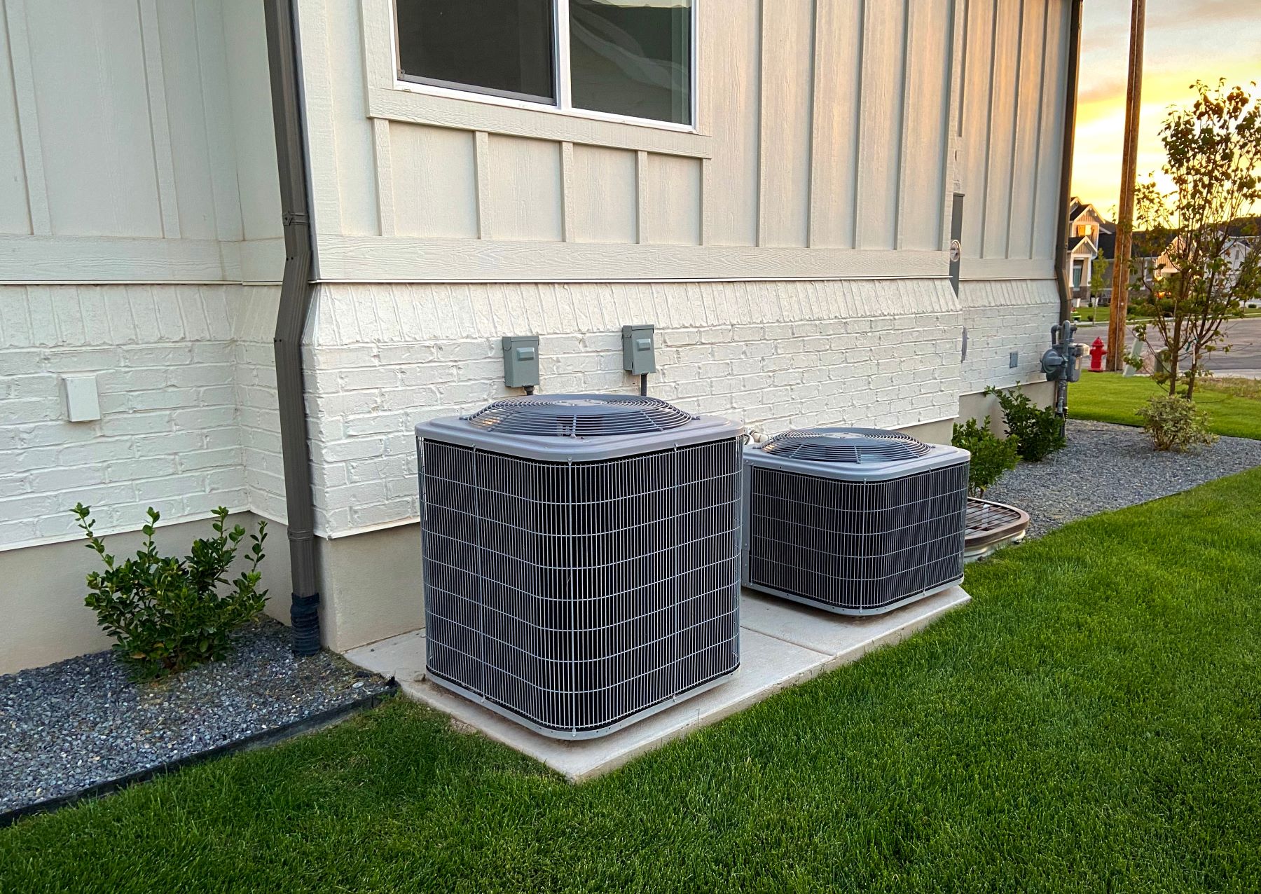 Air conditioning units installed outside a building, showcasing a zoning system setup with green grass and landscaping.