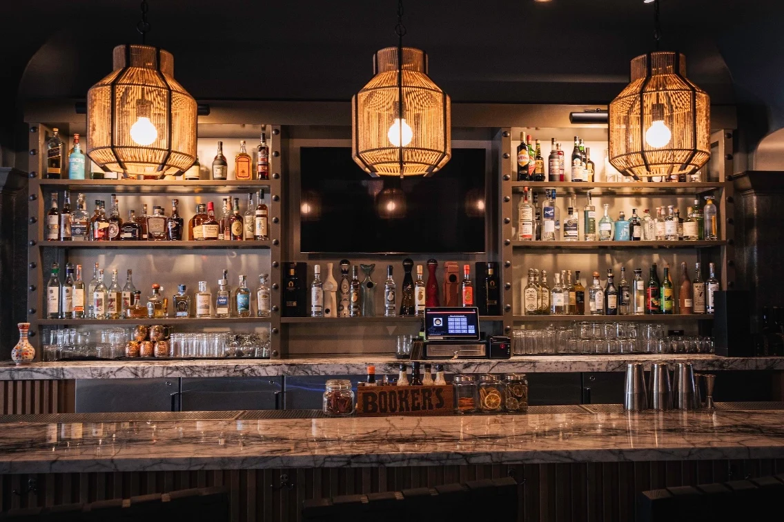 Elegant bar setup featuring a variety of bottles, hanging light fixtures, and a marble countertop at Liora Estate.
