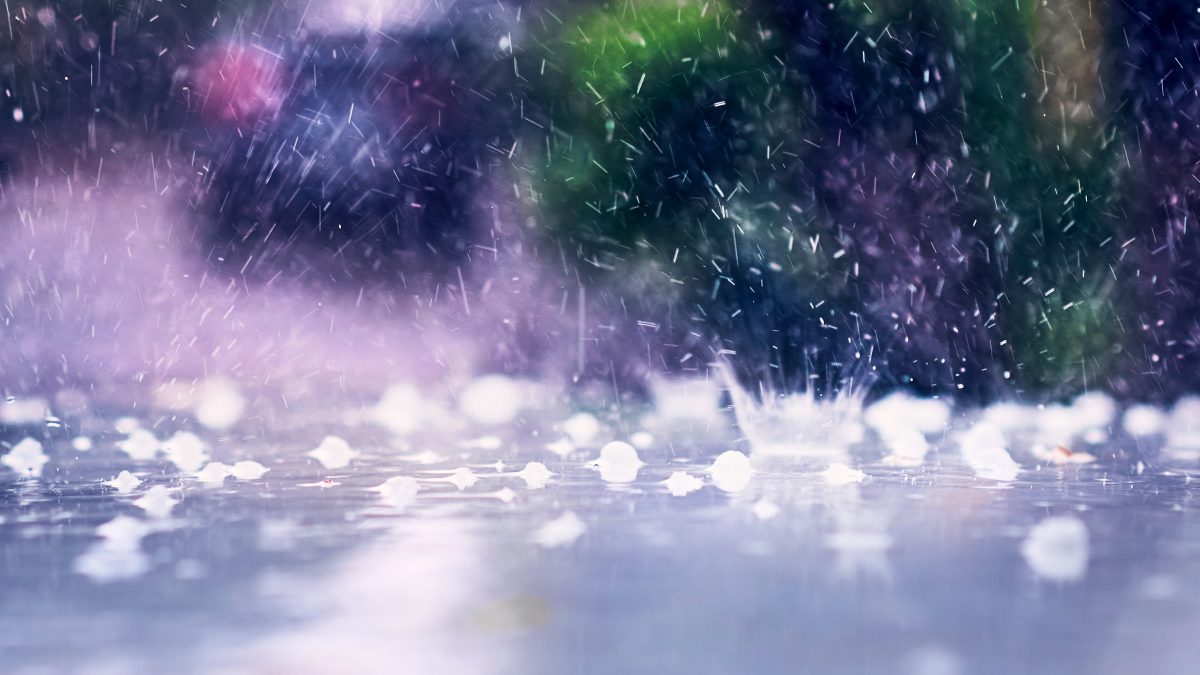 Heavy rain falling on a surface with splashes and hailstones, creating a stormy atmosphere.