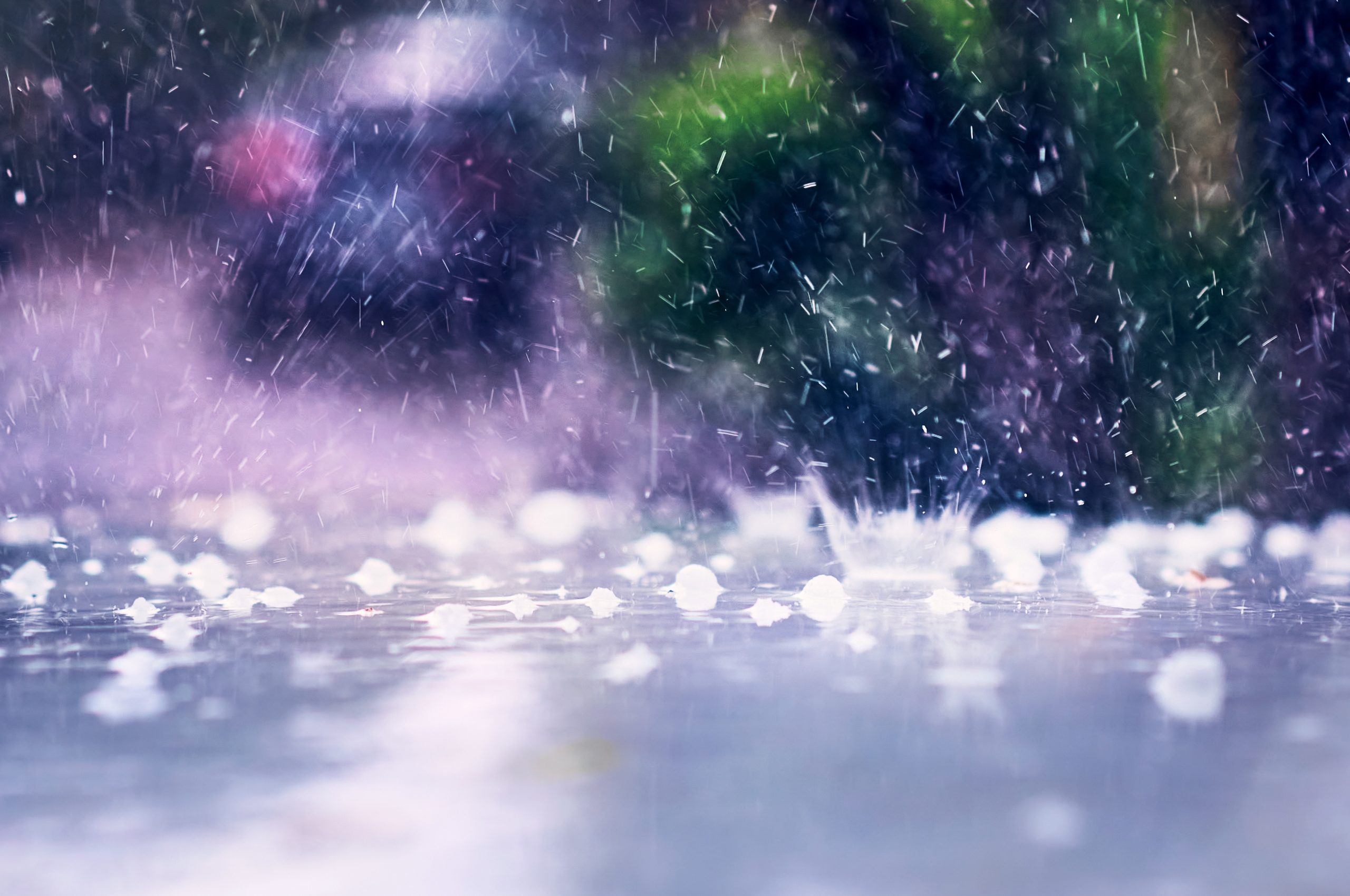 Heavy rain falling on a surface with splashes and hailstones, creating a stormy atmosphere.