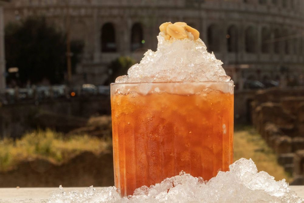 A refreshing cocktail with crushed ice and a garnish, set against a blurred historic backdrop.