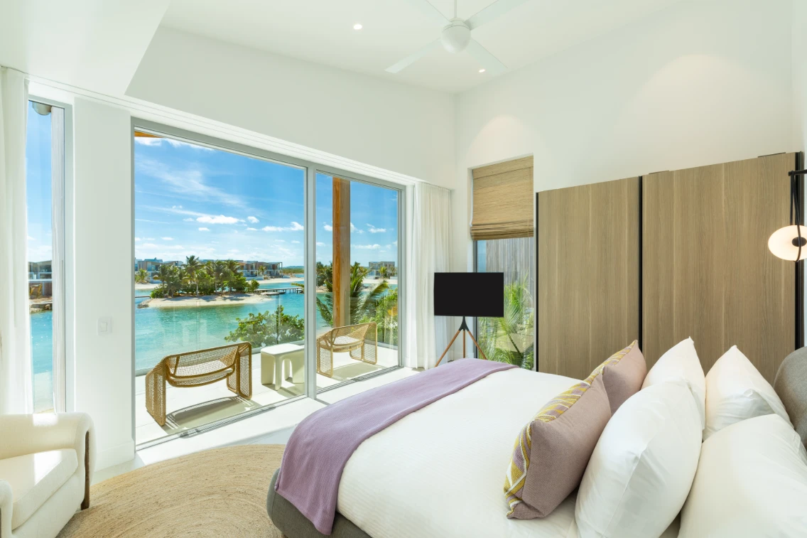 Modern bedroom with a view of the water, featuring a large window, comfortable bed, and stylish decor in Turks & Caicos.