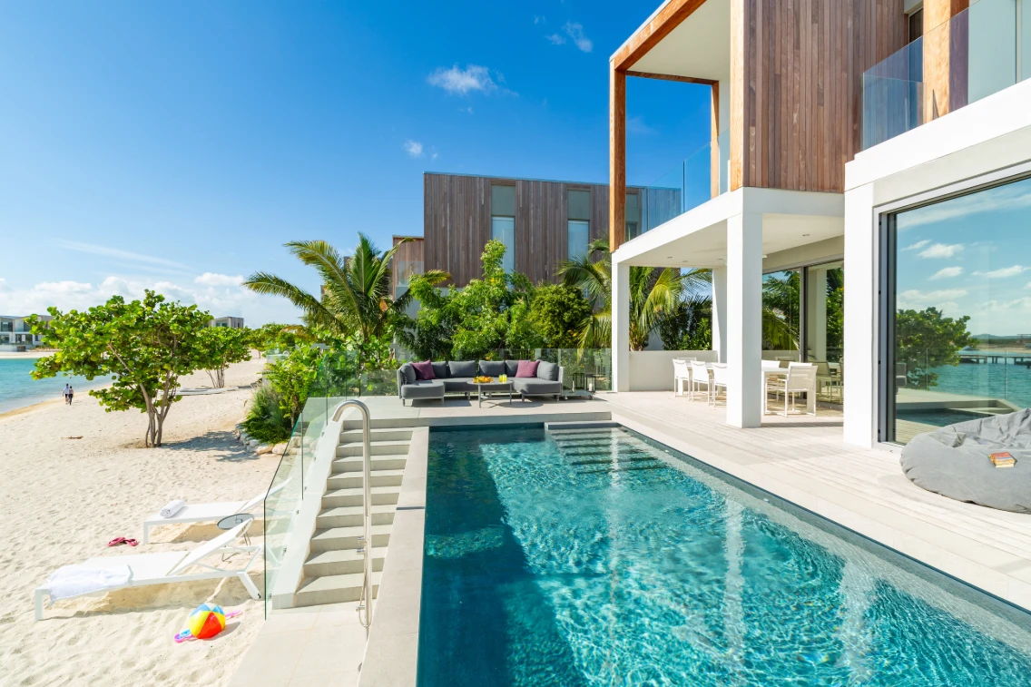 Luxury villa with a private pool, outdoor seating, and tropical surroundings near a beach in Turks & Caicos.