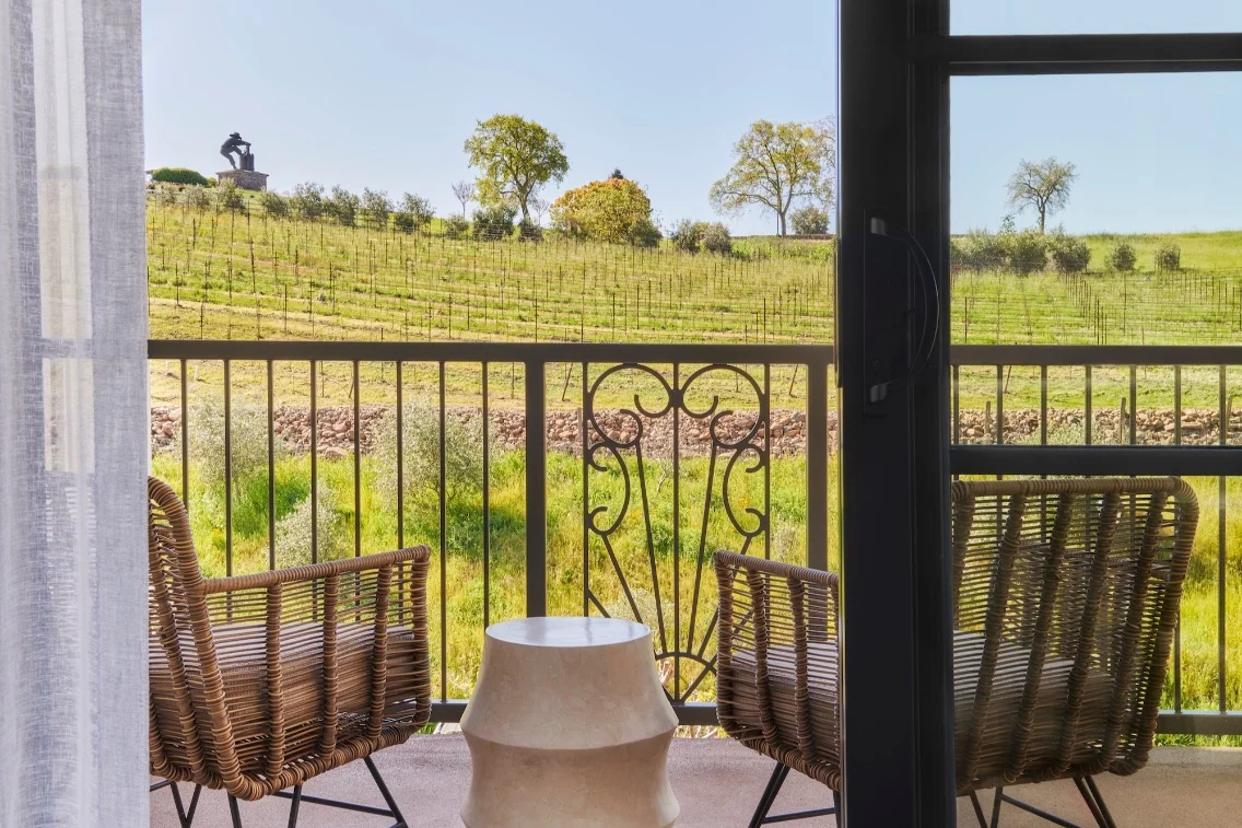 Balcony view overlooking lush vineyards with two chairs and a small table, highlighting the beauty of Napa Valley.