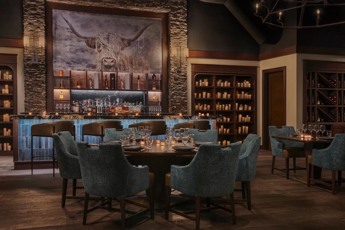 Elegant dining area at Meritage Resort, featuring a bar with various spirits and cozy seating surrounded by candlelit decor.