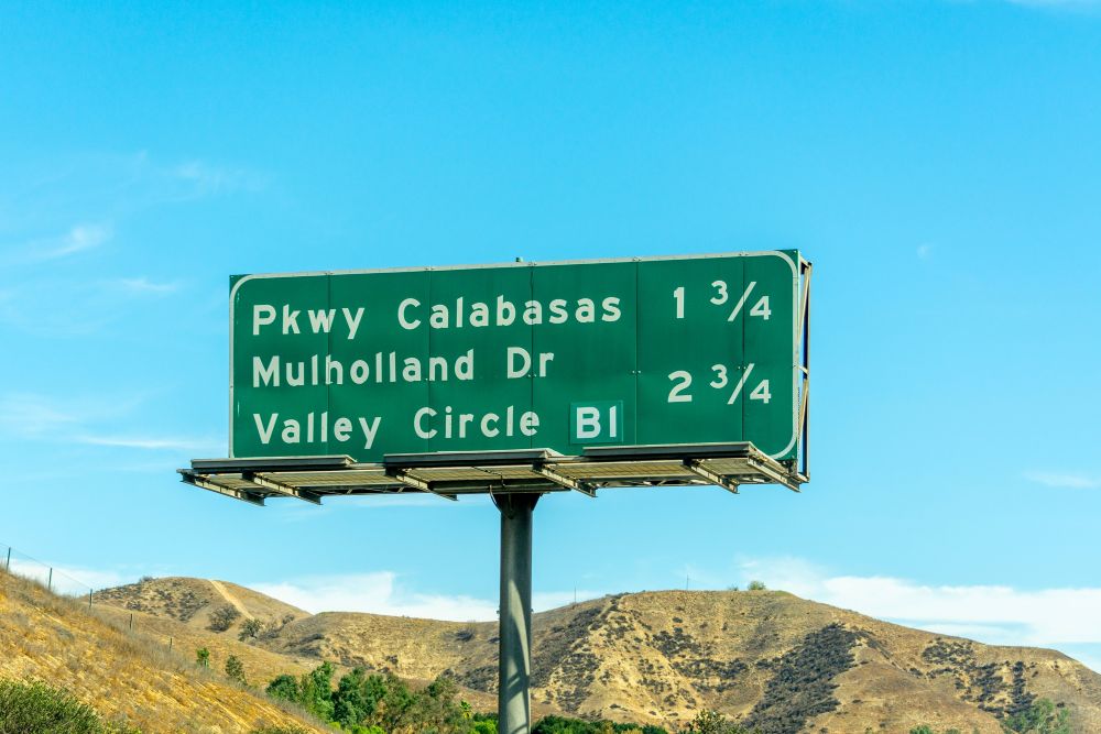 Road sign indicating directions to Parkway Calabasas, Mulholland Drive, and Valley Circle with distance markers.