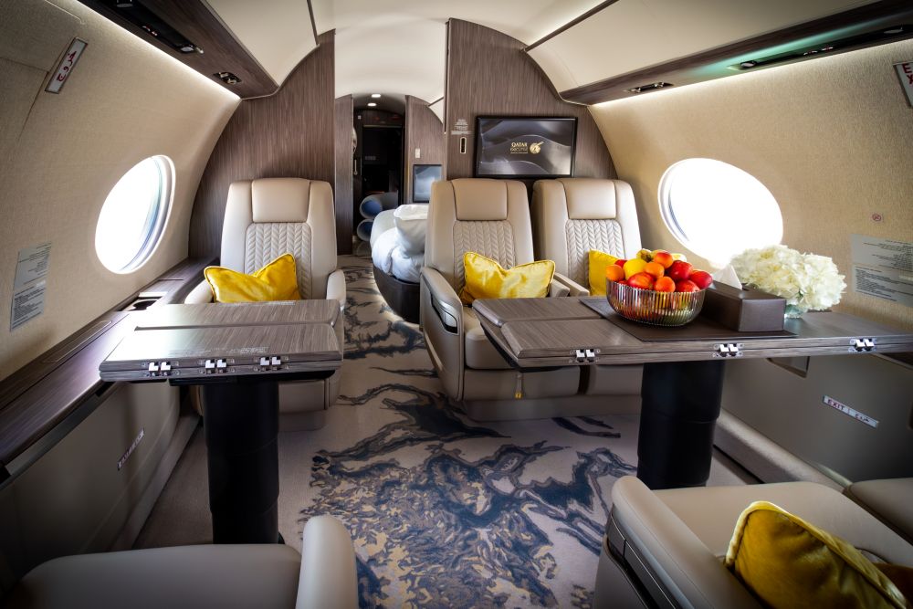 Luxurious interior of a private jet featuring comfortable seating, elegant decor, and a vibrant fruit bowl on a table.