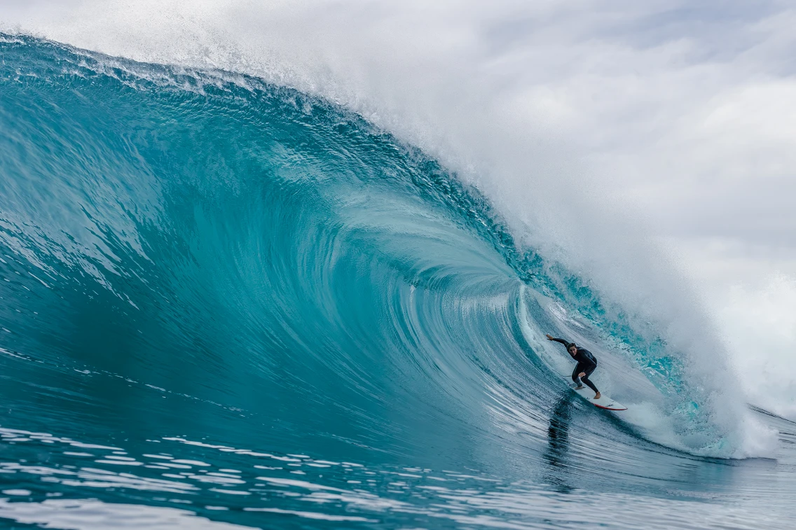 Surfer riding a powerful wave at a beach in San Diego, showcasing big-wave surfing technique and ocean safety.