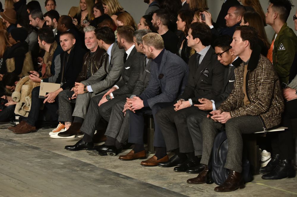 Men in stylish outfits seated in the front row at a fashion show, showcasing the latest trends in luxury style for Fall 2026.