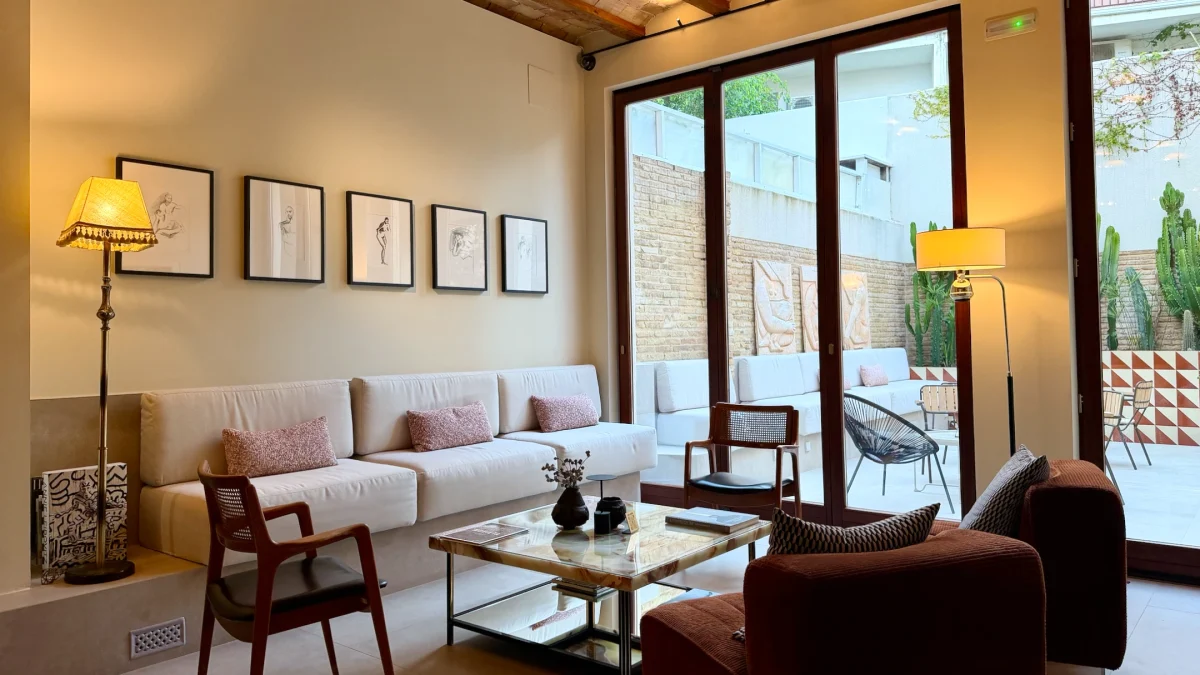 Modernist lounge area at La Novieta hotel featuring a comfortable seating arrangement and large windows overlooking a patio.