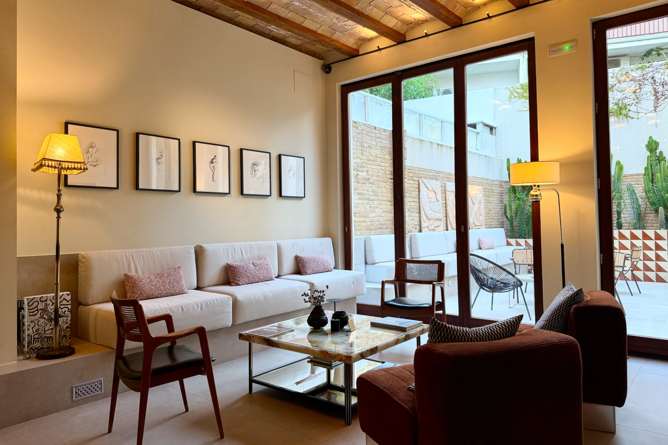 Modernist lounge area at La Novieta hotel featuring a comfortable seating arrangement and large windows overlooking a patio.