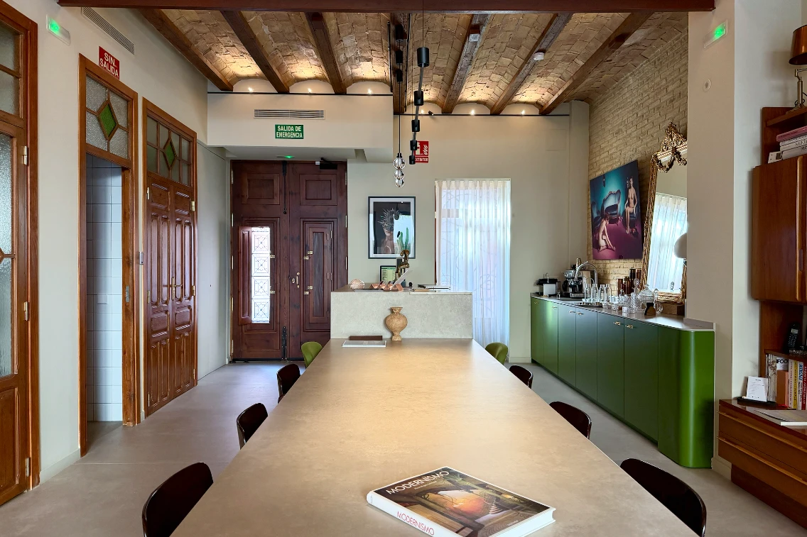 Modernist interior of La Novieta boutique hotel in Valencia, featuring a long table, stylish decor, and vibrant green cabinetry.