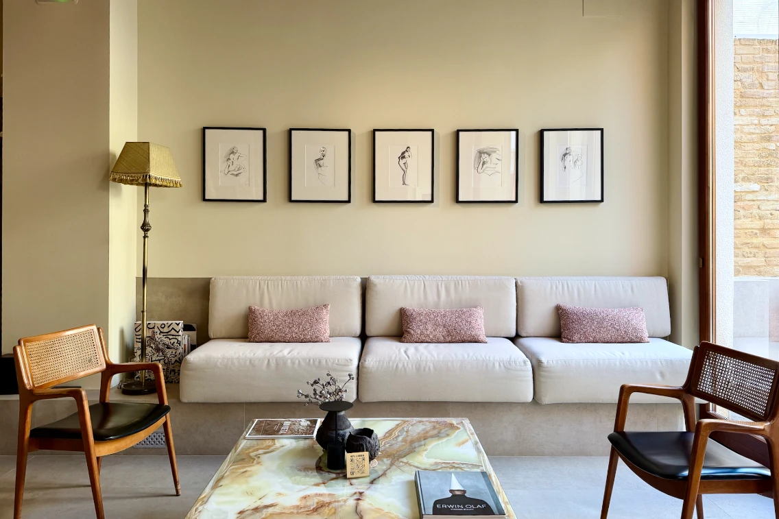 Chic hotel lobby featuring a modern sofa, accent pillows, artistic wall frames, and stylish furniture.