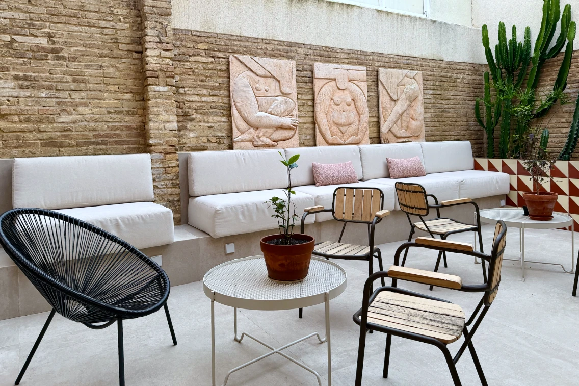 Stylish lounge area featuring modern seating, plant decorations, and artistic wall reliefs at La Novieta Boutique Hotel.