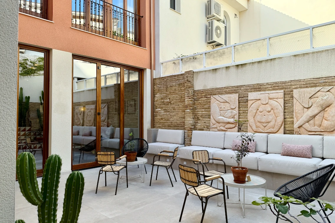 Outdoor seating area with modern furniture and textured wall art at La Novieta boutique hotel in Valencia.