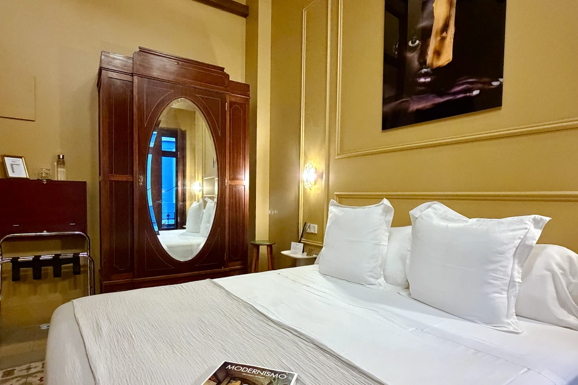 A cozy hotel room with a bed, wooden wardrobe, and modern decor, showcasing the elegant style of La Novieta in Valencia.