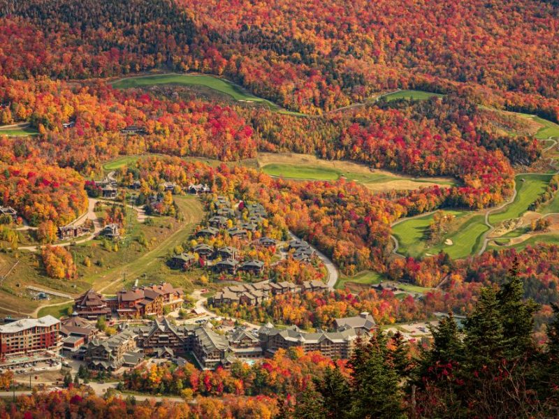 Colorful autumn foliage surrounds the Lodge at Spruce Peak and scenic golf course in Stowe, Vermont.