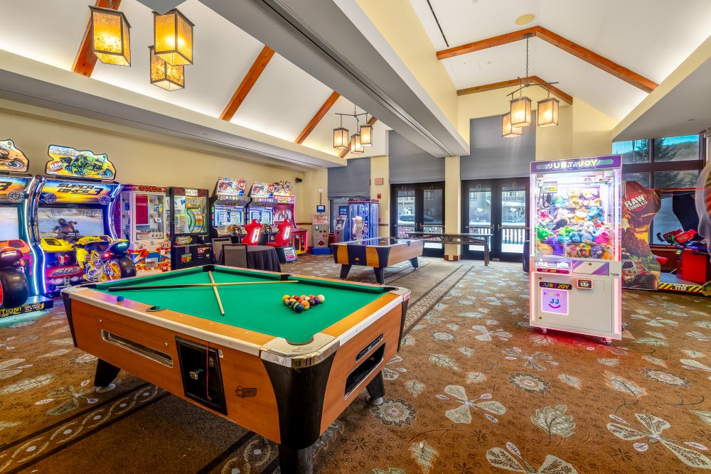 Game room with pool table, arcade machines, and a claw machine at The Lodge at Spruce Peak in Stowe, Vermont.