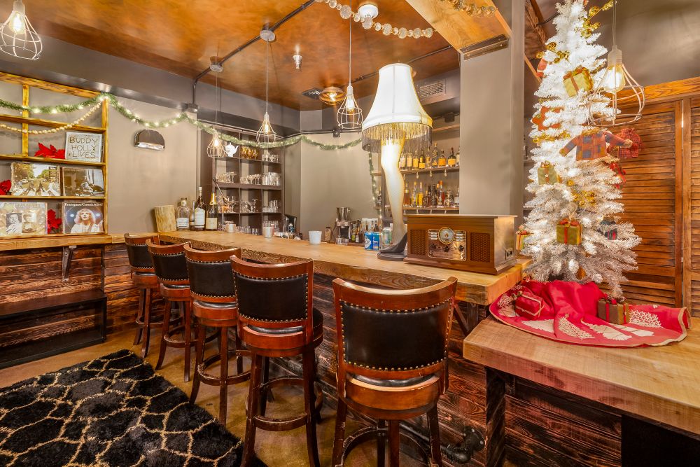 Cozy bar area with wooden stools, a festive white Christmas tree, and holiday decorations creating a warm atmosphere.