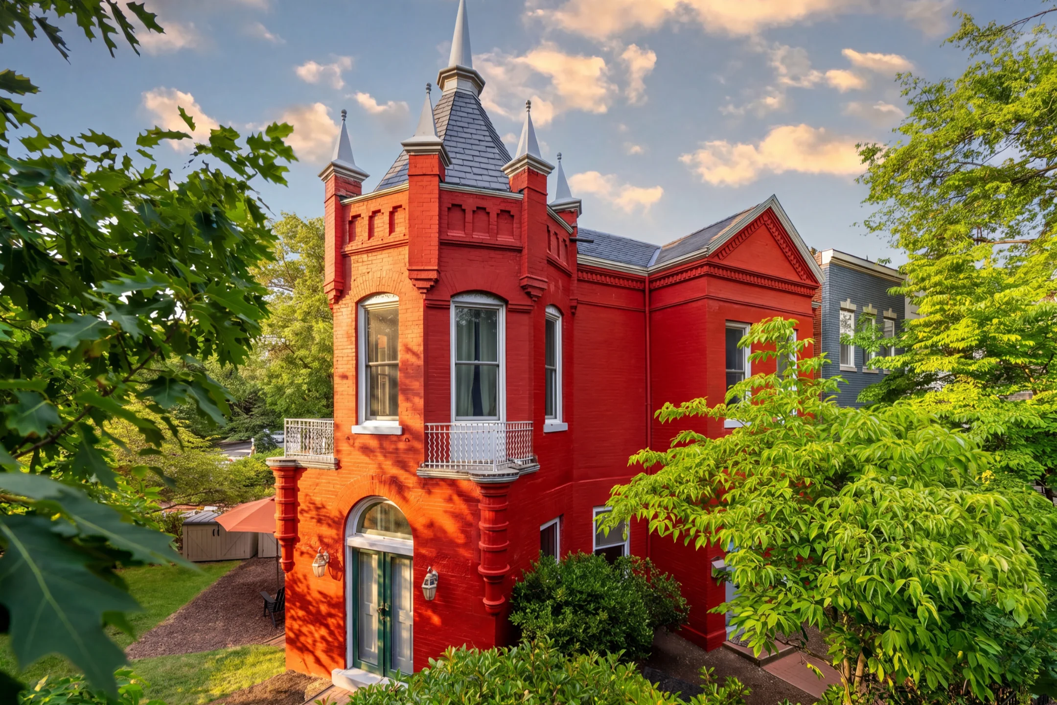 Victorian-style home with castle-like features surrounded by greenery in Capitol Hill, showcasing vibrant red brick and spires.