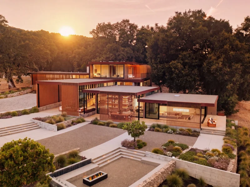 Modern architectural retreat in Carmel set against a sunset, showcasing landscaped gardens and elegant structures.
