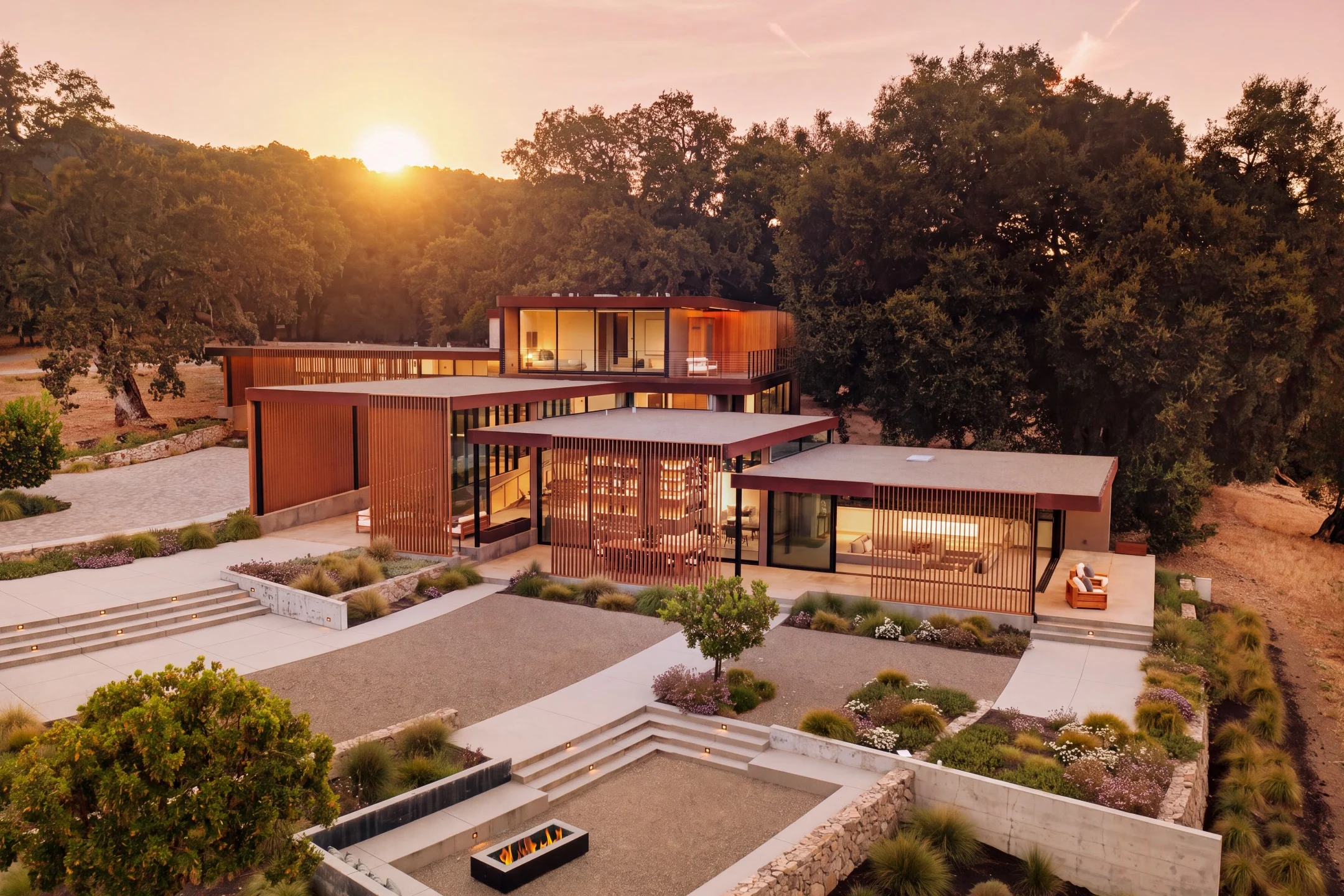 Modern architectural retreat in Carmel set against a sunset, showcasing landscaped gardens and elegant structures.
