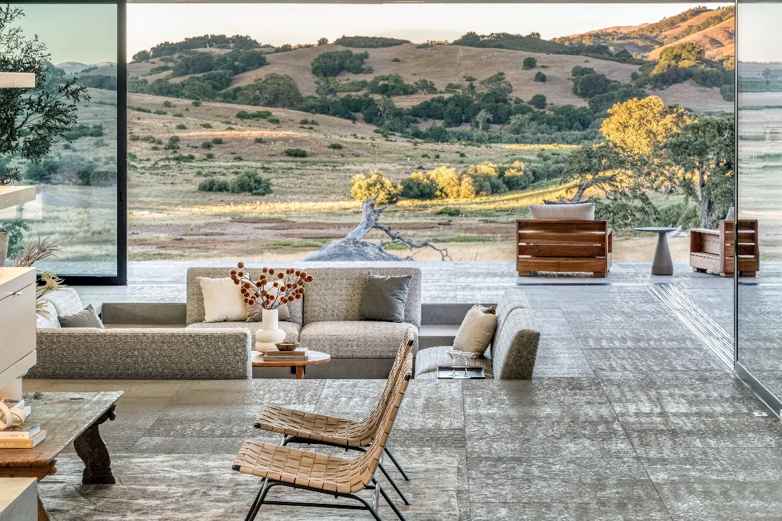 Modern interior of a spacious living area with panoramic views of rolling hills and lush greenery at a luxurious Carmel retreat.