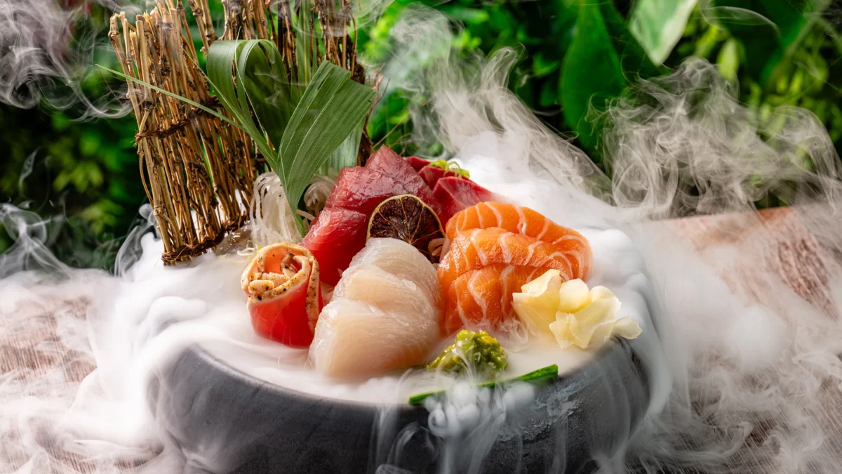 Sashimi platter presented with vibrant seafood and garnishes, surrounded by wisps of smoke on a rustic wooden table.