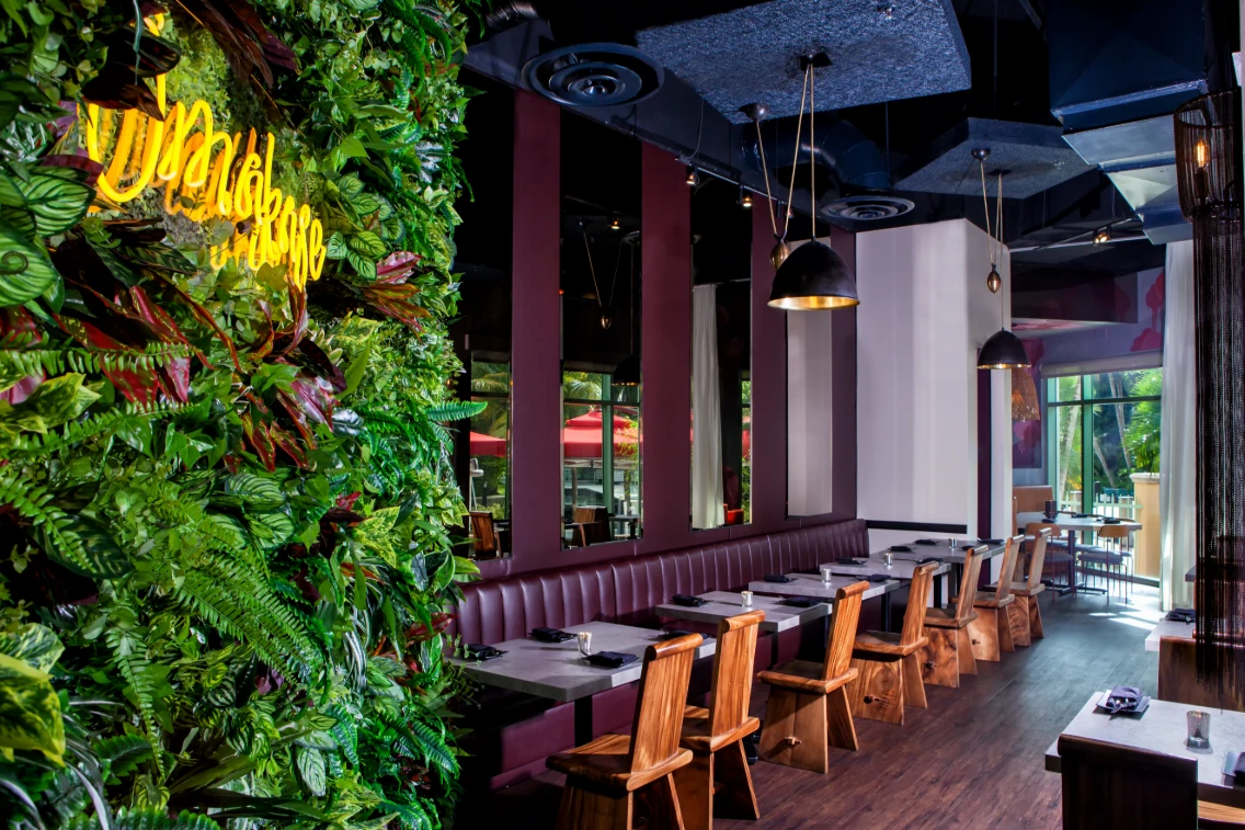 Lush greenery and modern decor create an inviting dining space at Casa Sensei on the Las Olas Waterfront.