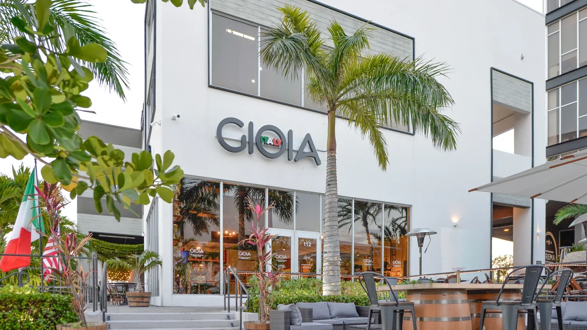 Gioia Italy restaurant exterior showcasing modern architecture and Italian elements, surrounded by greenery and outdoor seating.