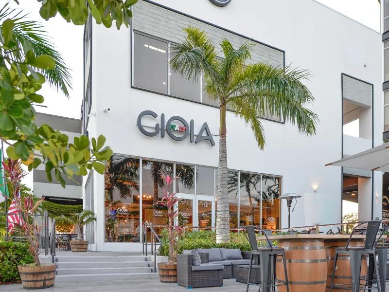 Gioia Italy restaurant exterior showcasing modern architecture and Italian elements, surrounded by greenery and outdoor seating.